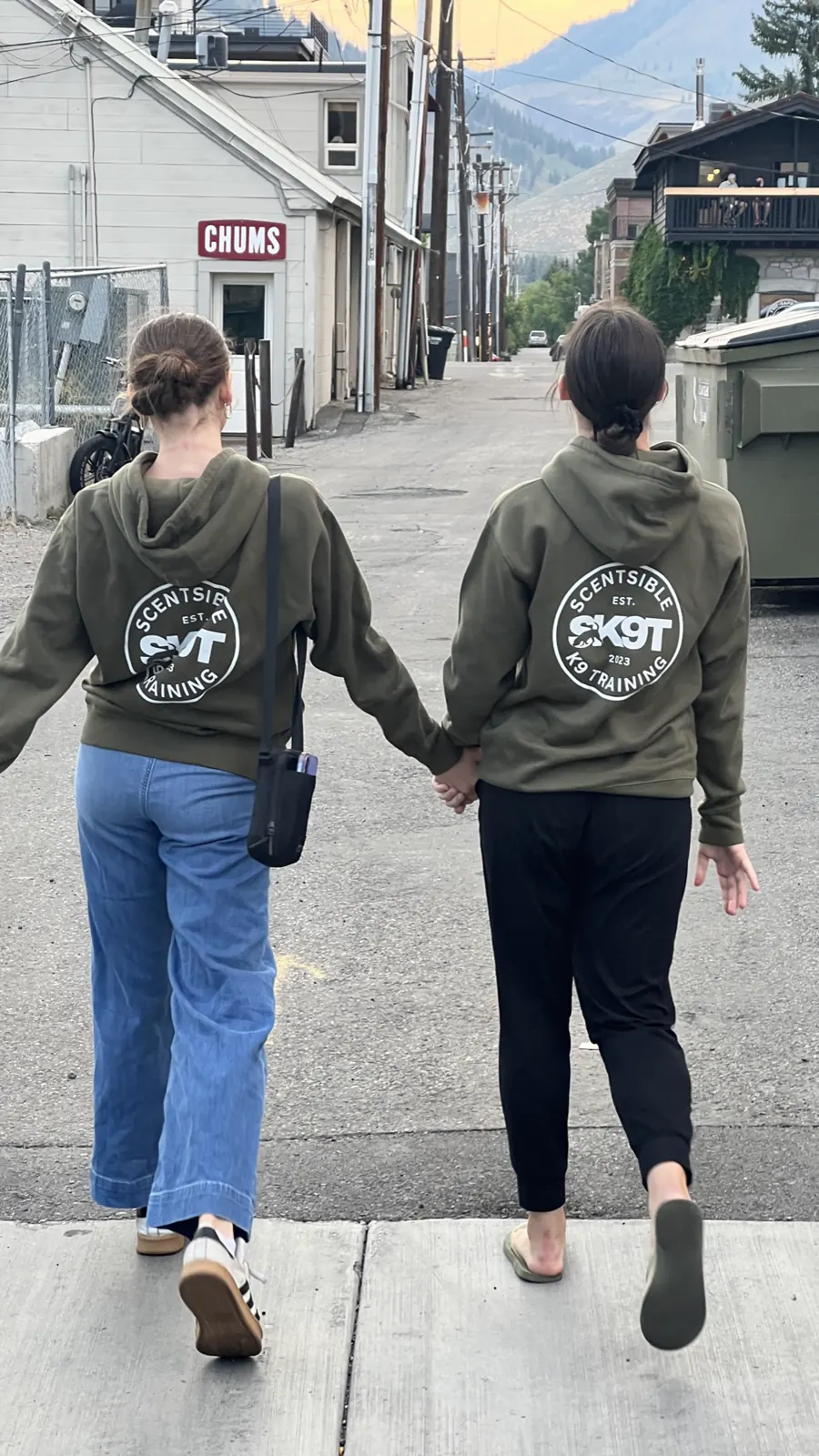 Two Scentsible K9 trainers in branded hoodies walking away down an alley