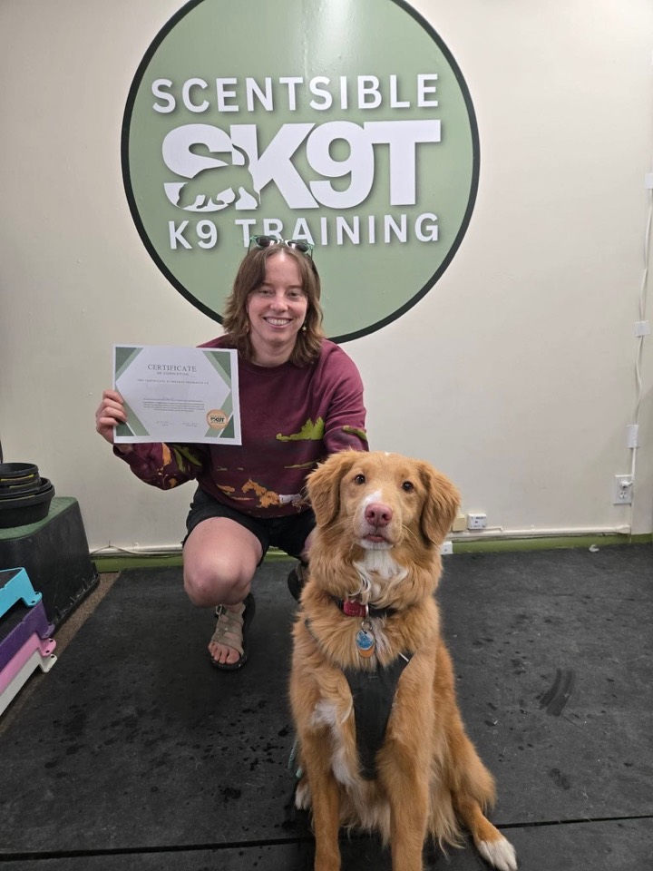A client and their retriever with a graduation certificate