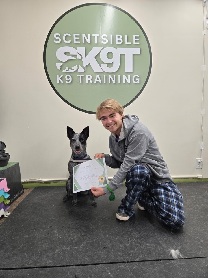 A client and their dog with a graduation certificate